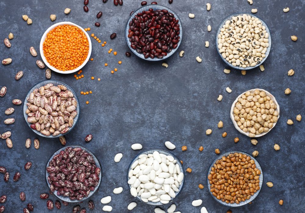 Legumes and beans assortment in different bowls on light stone b